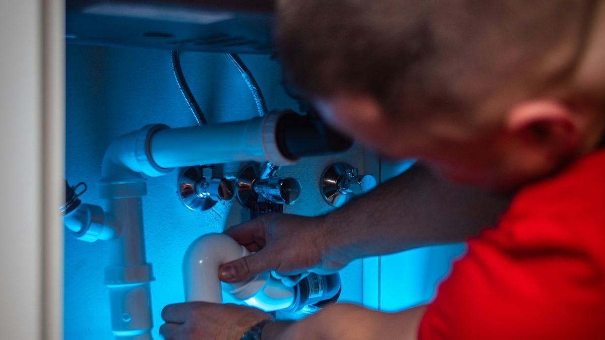 Technician working on pipes under a sink